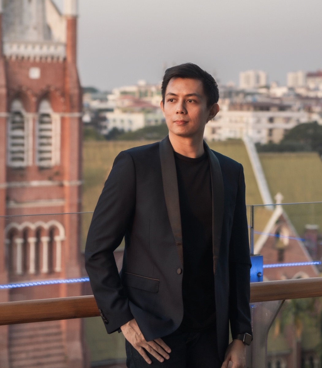 Dr. Ye Yint standing outdoors on a balcony